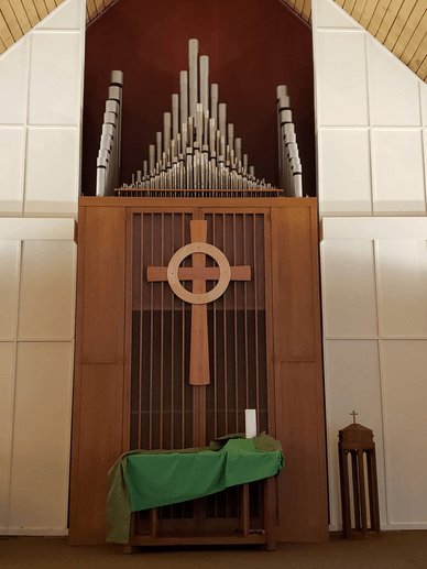 Wooden Celtic cross hangs on organ pipes enclosure in the Sanctuary